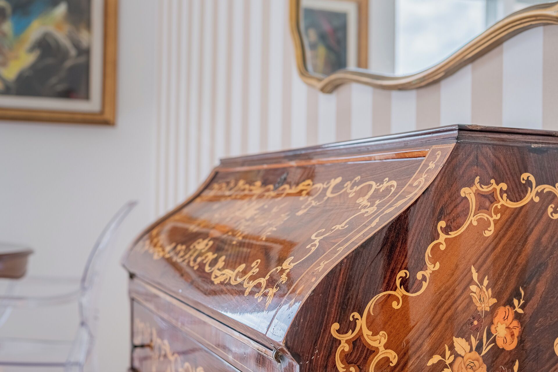 A wooden cabinet with intricate gold detailing and a glass top.