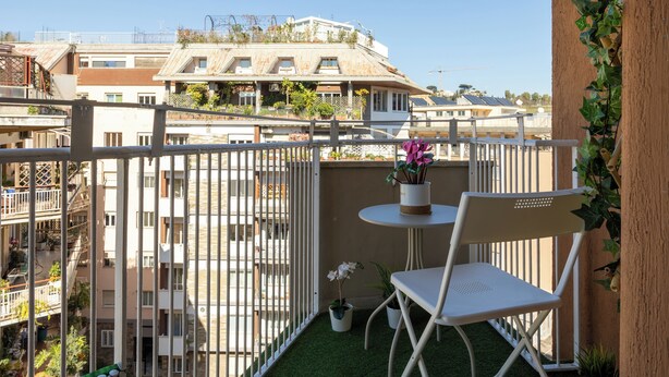En balkon med hvid stol og lille bord, omgivet af et hvidt gelænder.