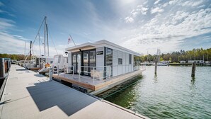 Een moderne steiger met een drijvende constructie, een overdekt gedeelte en uitzicht op het water.
