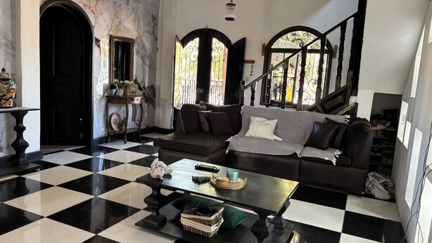 A living room with a checkered floor, a sofa, a coffee table, and a staircase with a view.