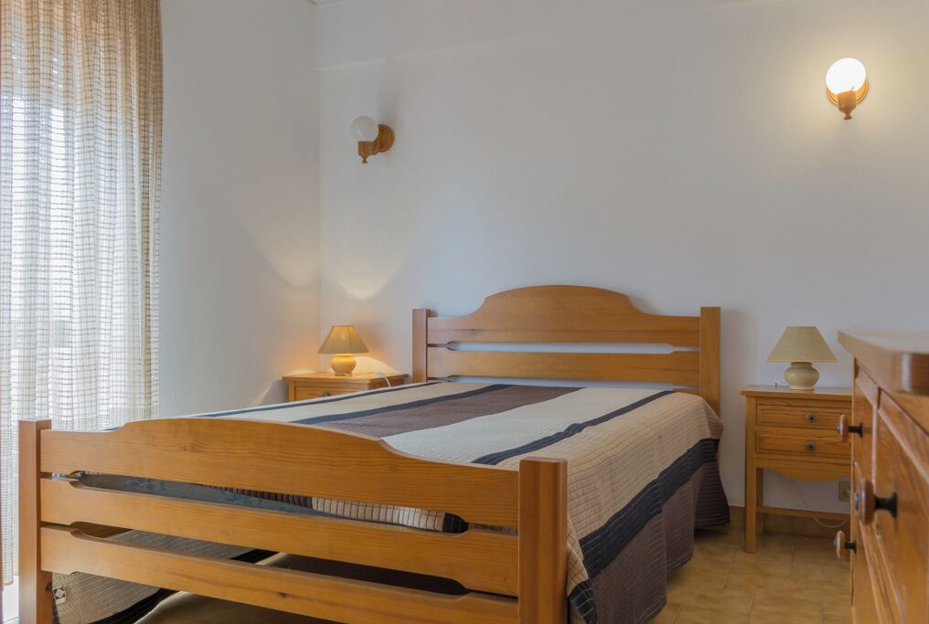 Une chambre à coucher avec un lit en bois, des tables de chevet avec des lampes et un luminaire fixé au mur.