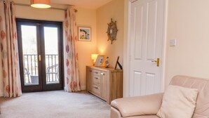 A living room with a beige leather sofa, a wooden cabinet, and a door with a brass handle.