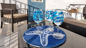 Ein Tisch mit zwei blauen Cocktails, einer gewebten Tischläufer und einem Korbstuhl.