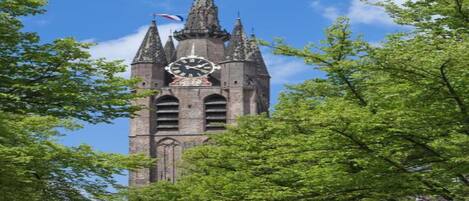 A historic clock tower with a clock face, surrounded by lush green trees.