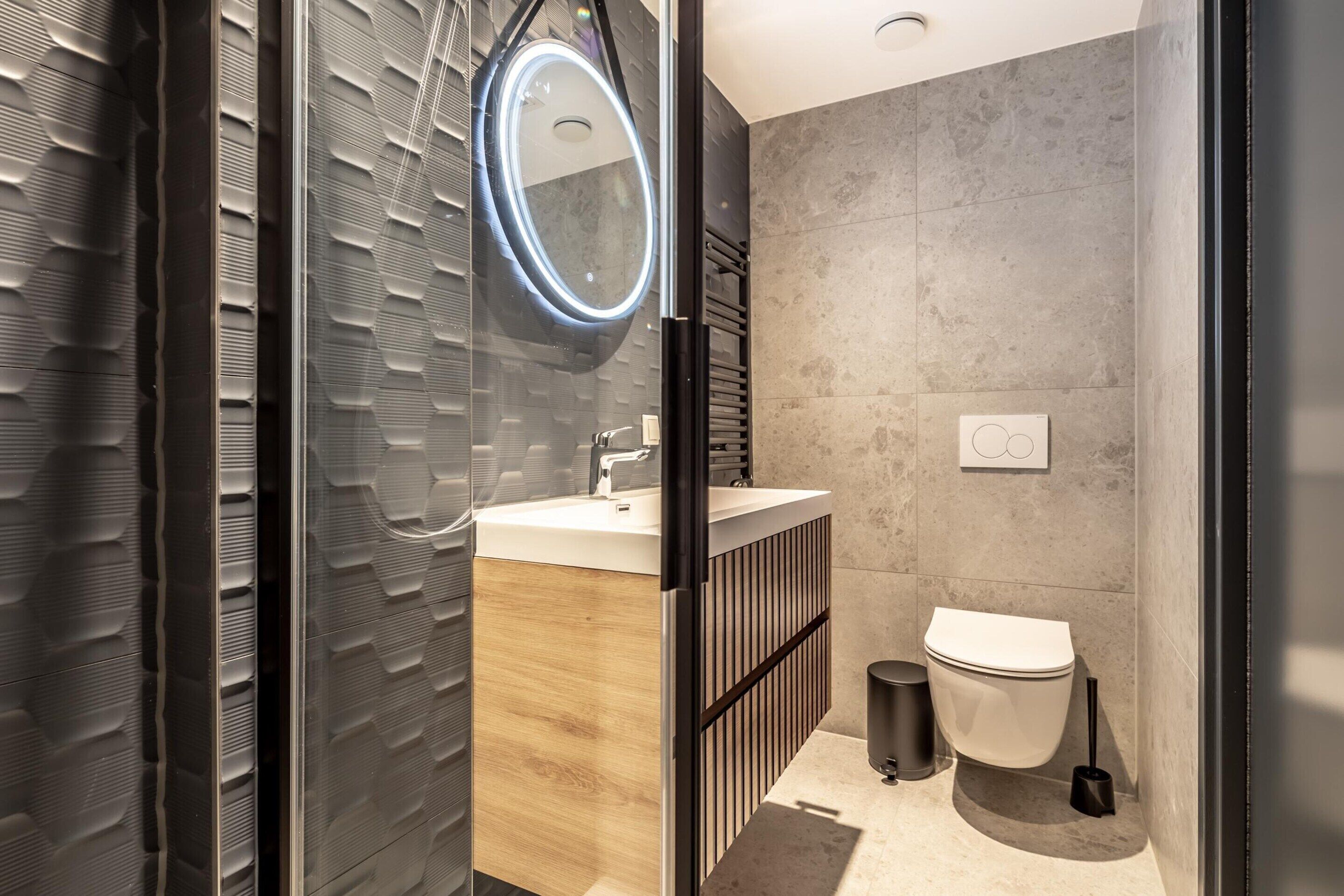A modern bathroom with a wooden vanity, a toilet, and a shower area.