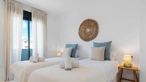 A hotel room with two beds, a large window, and a decorative wall piece.