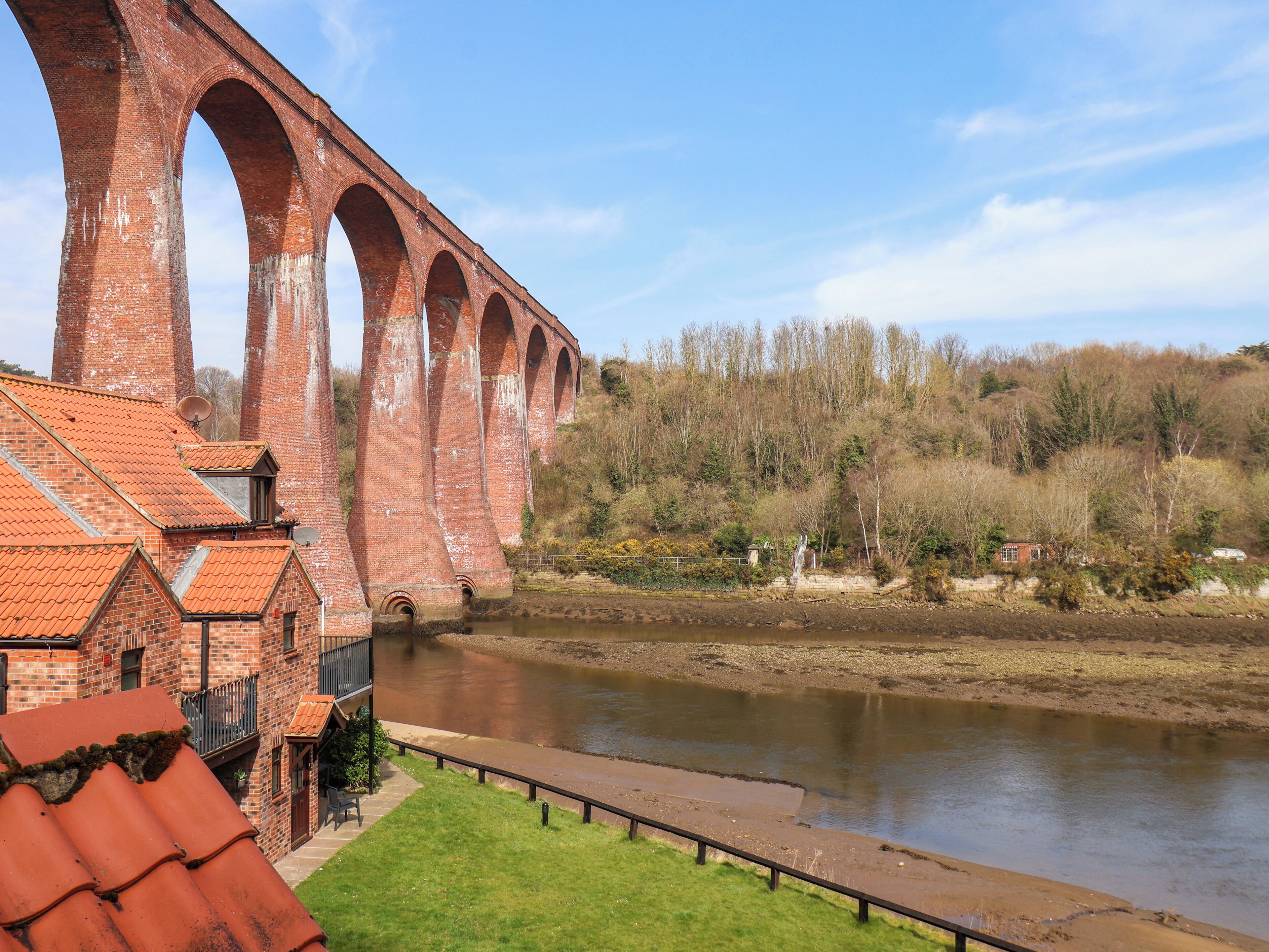 A brick bridge over a river with a small building adjacent to it.