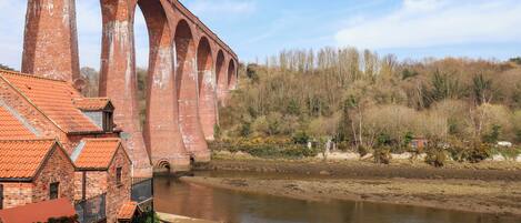 A brick bridge over a river with a small building adjacent to it.