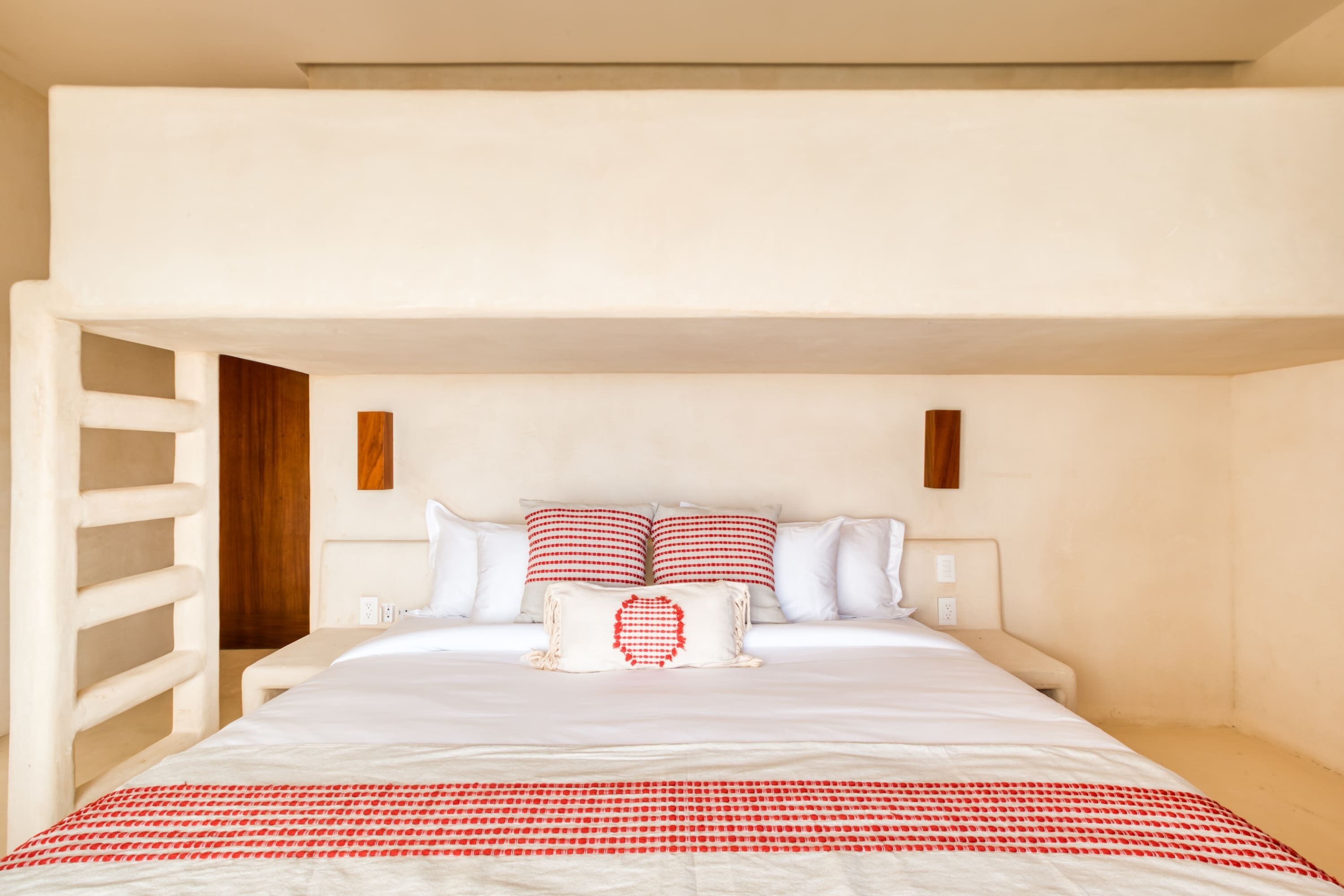 A bedroom with a bed, white walls, and a wooden door.