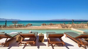 A poolside area with lounge chairs and a view of the ocean. - Beachfront Vista Villa (La Ventana)