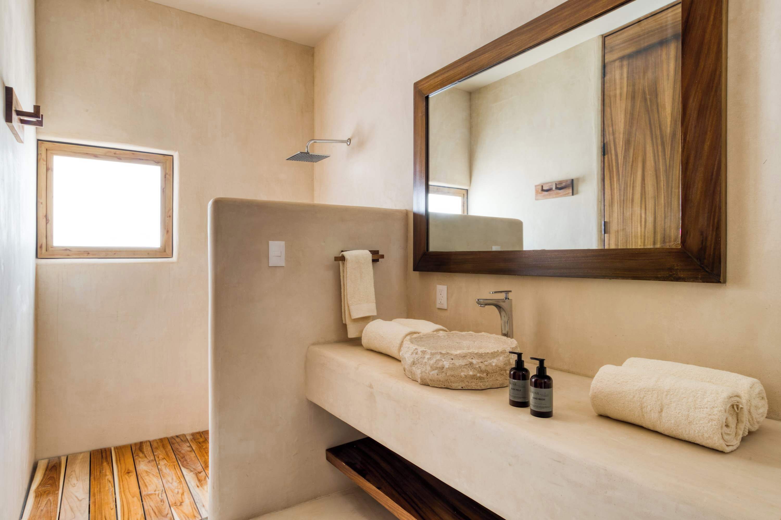 Une salle de bain avec un grand miroir, un lavabo, une douche et une fenêtre.