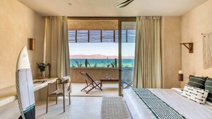 A hotel room with a bed, a desk, a chair, and a view of the ocean. - Oceanview Vista Villa (La Ventana)