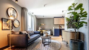 A modern living room with a sofa, a coffee table, and a large potted plant. - Stylish 2-bedroom Apartment in Delft (Delft)