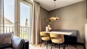 A modern dining area with a wooden table and chairs, a bench, and a hanging light fixture. - Stylish 2-bedroom Apartment in Delft (Delft)