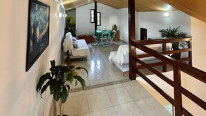 Ein geräumiges Zimmer mit Holzbalkendecke, einem Essbereich mit Tisch und Stühlen sowie einem Bett mit weißer Bettdecke.