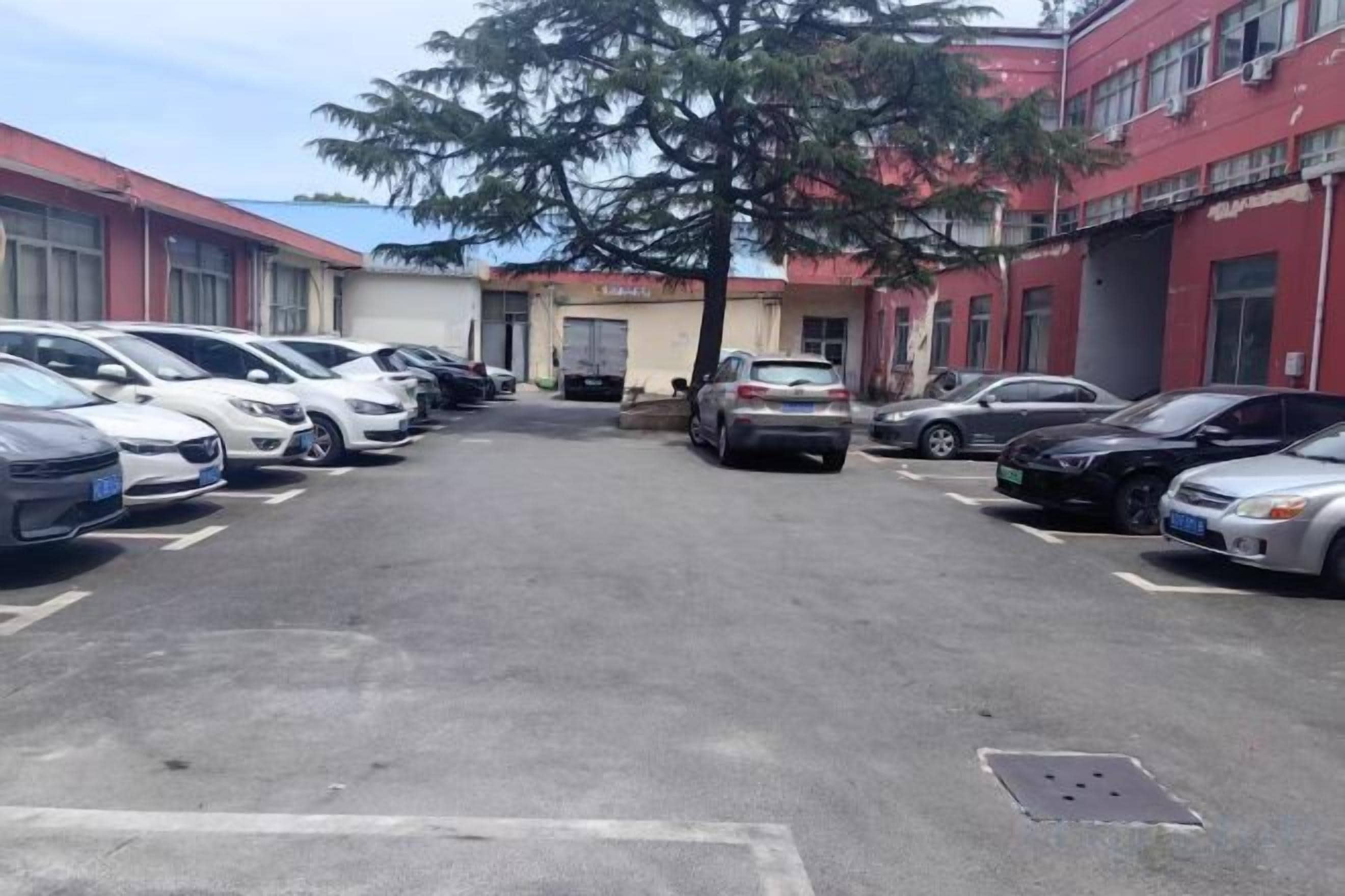 Un estacionamiento con varios autos estacionados frente a un edificio con paredes exteriores rojas y blancas.