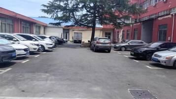 Un estacionamiento con varios autos estacionados frente a un edificio con paredes exteriores rojas y blancas.