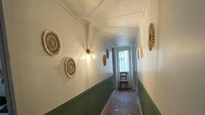Ein schmaler Flur mit grün gestrichenen Wänden, einem Backboden und dekorativen Wandleuchten.