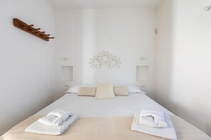 A minimalist hotel room with a single bed, two bedside tables, and a decorative wall piece.