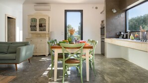 A dining area with a wooden table and chairs, a cabinet with glass doors, and a view through a large window.