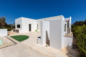 Una casa moderna blanca con un patio, una piscina y una escalera que lleva a un área cubierta.