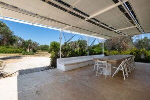 Un patio al aire libre con un banco blanco, una mesa y sillas.