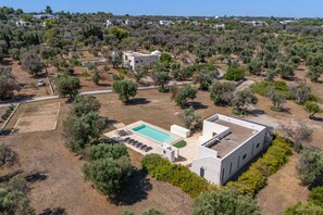Zona residencial con piscina, un edificio blanco y vegetación circundante.