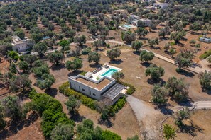 Vue aérienne d’un quartier résidentiel avec de nombreuses maisons, une piscine et la végétation environnante.