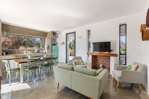 Un espacio moderno para vivir con comedor, sofá, televisor y chimenea.