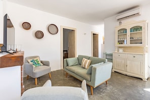 Una sala de estar con un sofá, sillones, un armario y un espejo.