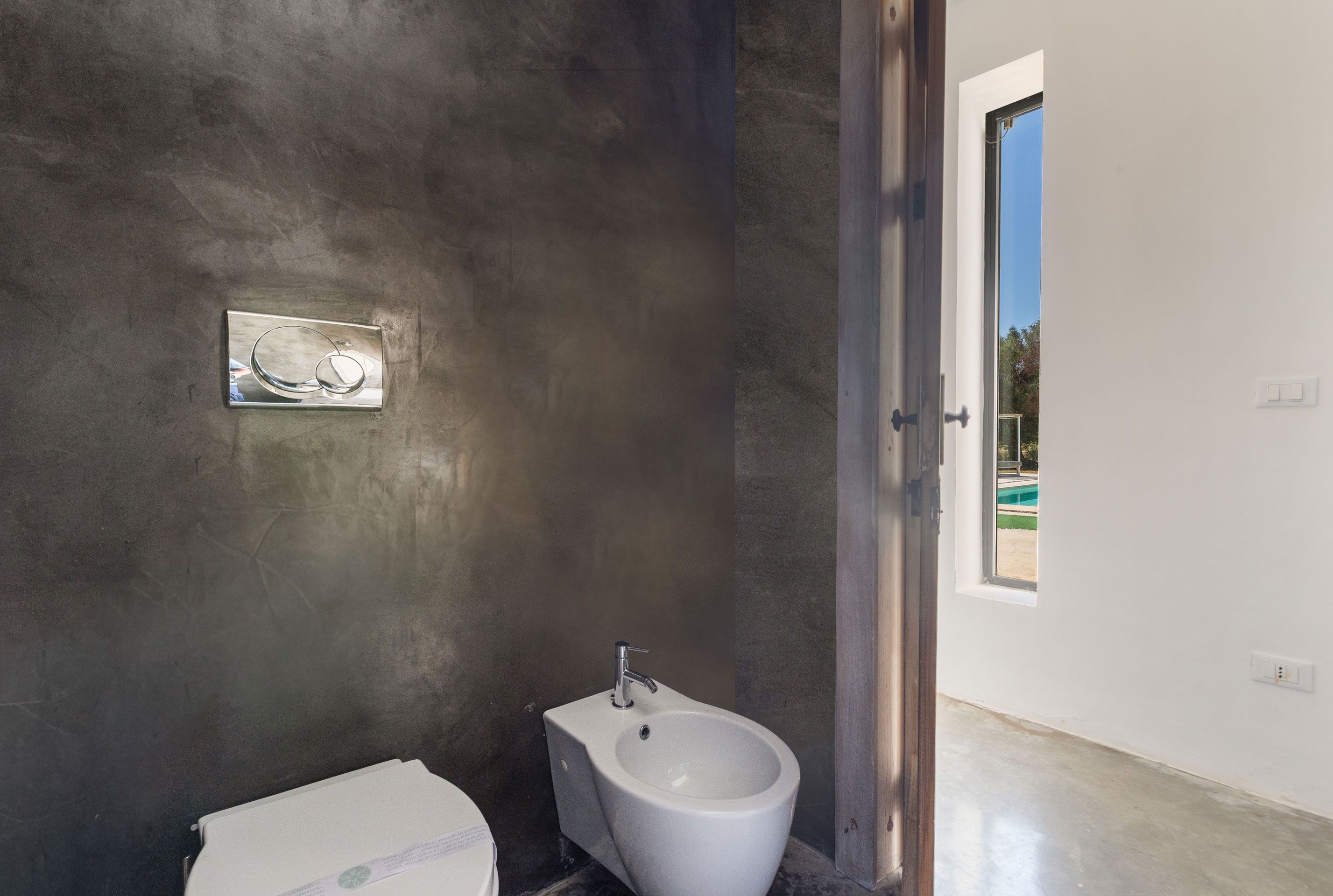 A modern bathroom with a bidet, a towel, and a large window.