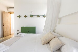 Un dormitorio con una cama, un aparador verde y una lámpara fijada a la pared.