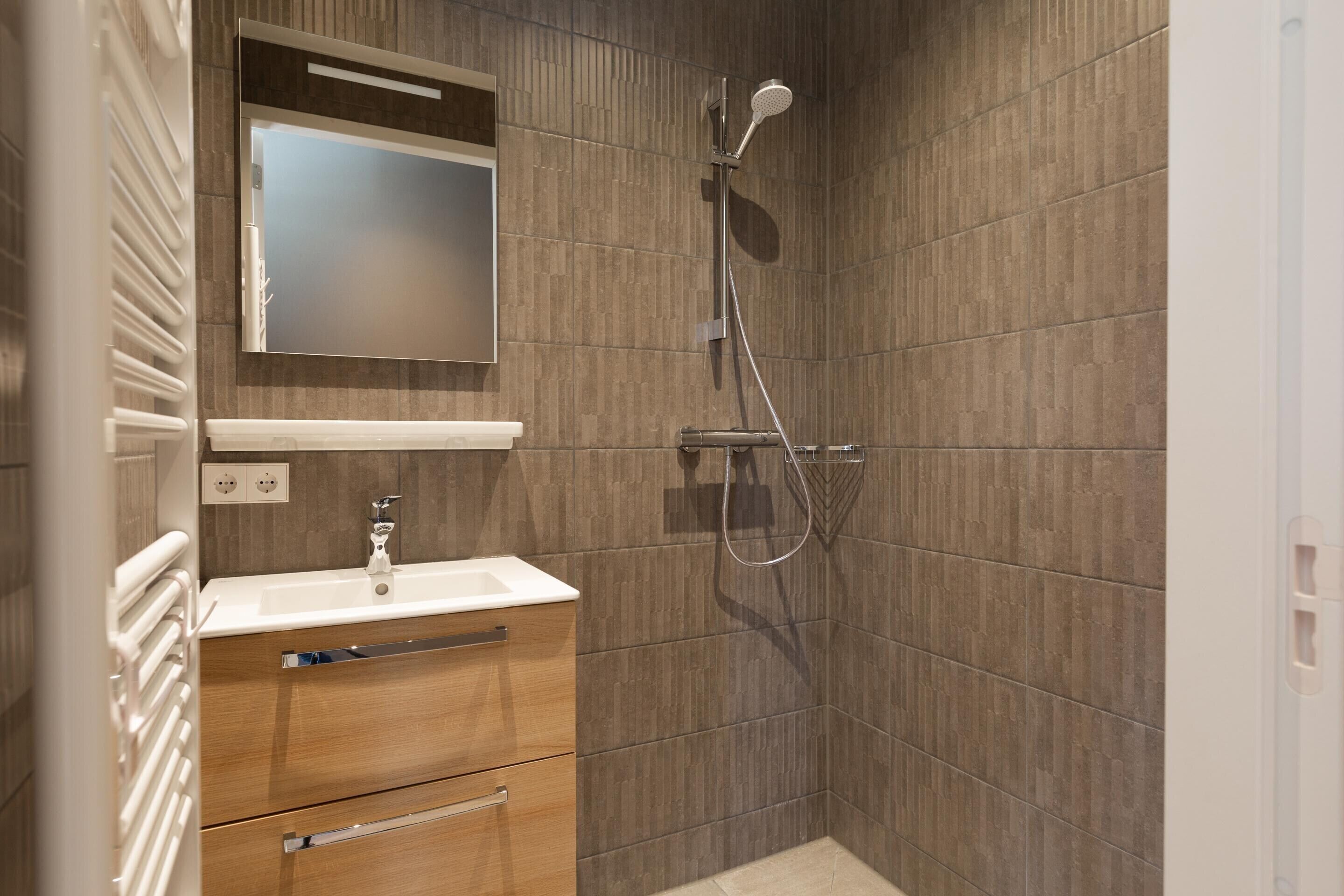 A modern bathroom with a shower, a sink, and a vanity with drawers.