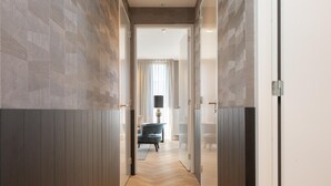 A hallway with wooden flooring and walls, leading to a room with a blue chair and a lamp. - Stylish Penthouse With 2 Bedrooms (The Hague)