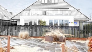 Et toetagers hus med tegltag, træhegn og et skilt, der siger "Happy Stay by VHB".
