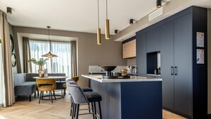 Una cocina moderna con una isla central, armarios oscuros e iluminación colgante.