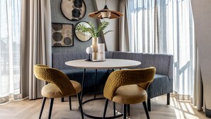 Un comedor moderno con una mesa redonda, dos sillas, una lámpara colgante y un sofá.