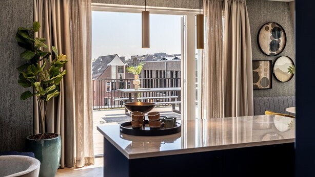 Una cocina moderna con un ventanal amplio, una planta en maceta y un comedor con mesa y sillas.