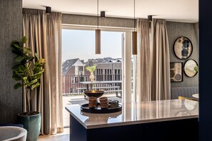 A modern kitchen with a large window, a potted plant, and a dining area with a table and chairs. - Delft Escape With Rooftop and Wifi (Delft)