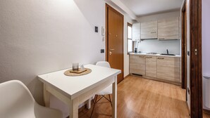 A compact kitchen with wooden cabinets, a white countertop, and a door leading to another room. - Emilia Studios 7 (Modena)