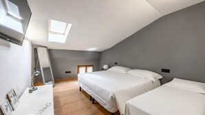 A bedroom with a skylight, a desk with a lamp, and two beds. - Emilia Studios 7 (Modena)