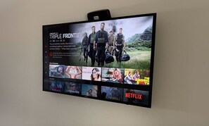 Un téléviseur à écran plat affichant l’interface de Netflix, avec différentes miniatures de films.