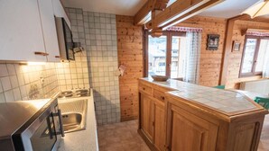 Een keuken met houten kastjes, een betegelde achterwand en een groot raam.