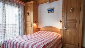 Een slaapkamer met een bed, een houten kledingkast en een nachtkastje.