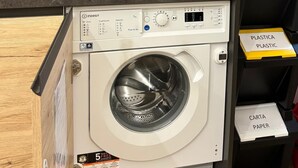 A compact washer and dryer unit with a control panel, placed in a modern kitchen setting.