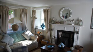 Un salon chaleureux avec une cheminée, un canapé, une table basse et une fenêtre avec des rideaux.