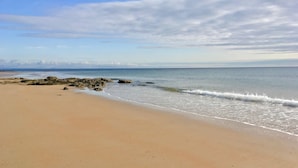 Une plage de sable fin, avec des vagues douces et un ciel dégagé.