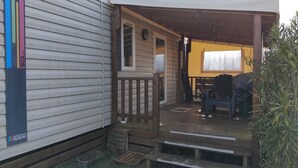 Una casa móvil con porche, un pequeño espacio exterior para sentarse y un jardín.