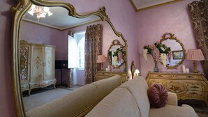 A room with a large ornate mirror, a cream-colored sofa, a gold-framed dresser, and a pink wall. - VACATIONS IN THE HEART OF ROME COLOSSEUM (Roma)