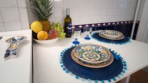 A kitchen counter with a bowl of fruit, a bottle of wine, and decorative plates. - VACATIONS IN THE HEART OF ROME COLOSSEUM (Roma)